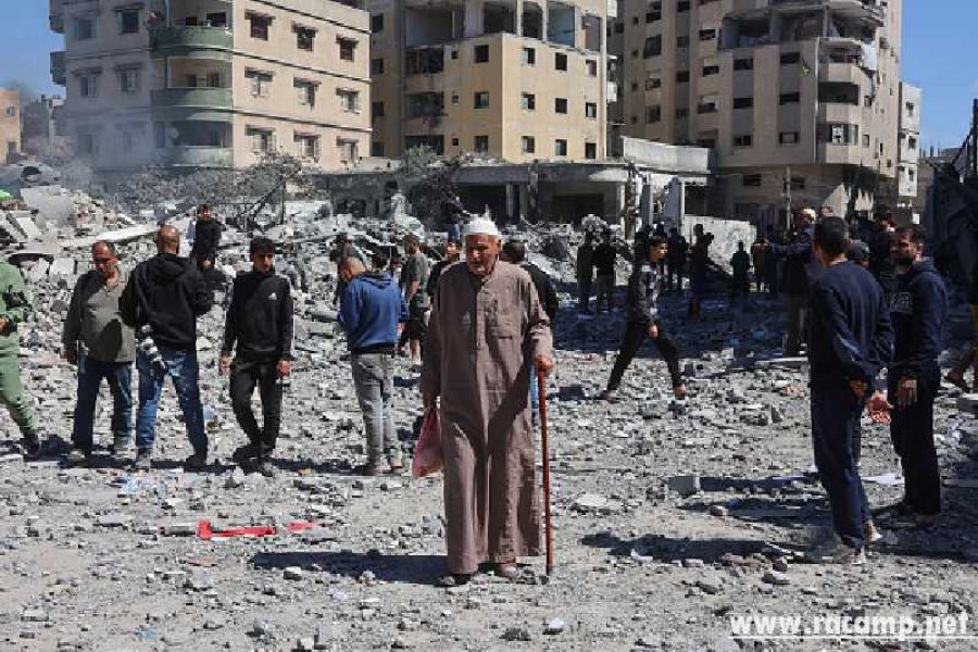 An elderly Palestinian man walks past people gaathered near the rubble of the Elias Tarazi family house, after it was destroyed in an Israeli strike in al-Sabra neighbourhood in Gaza City on March 19, 2025. (Photo by Omar AL-QATTAA / AFP) (Photo by OMAR AL-QATTAA/AFP via Getty Images)
